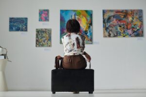 Vrouw kijkt naar schilderijen die aan de muur hangen